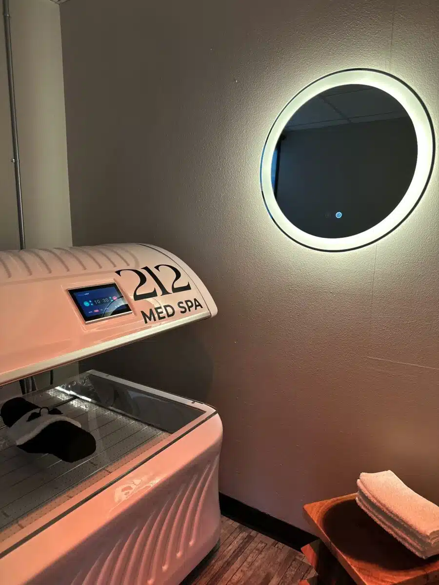 A corner of a therapy bed with a illuminated mirror on the wall