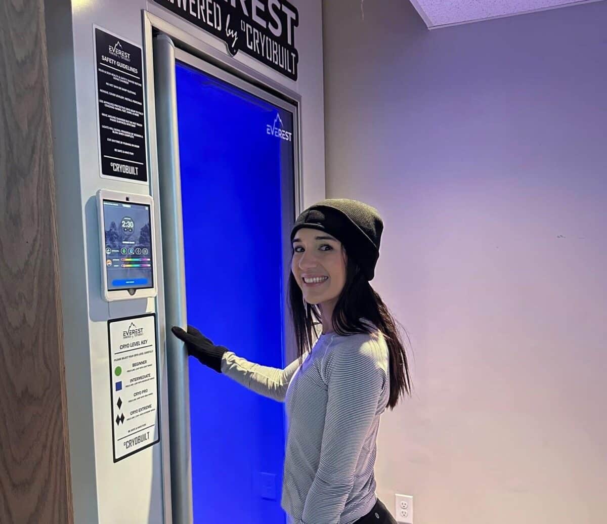 Woman standing next to Cryobuilt chamber at 212 Med Spa in Edmonds